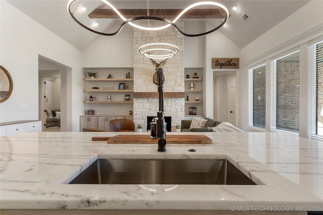 kitchen featuring visible vents, high vaulted ceiling, light stone counters, and a sink