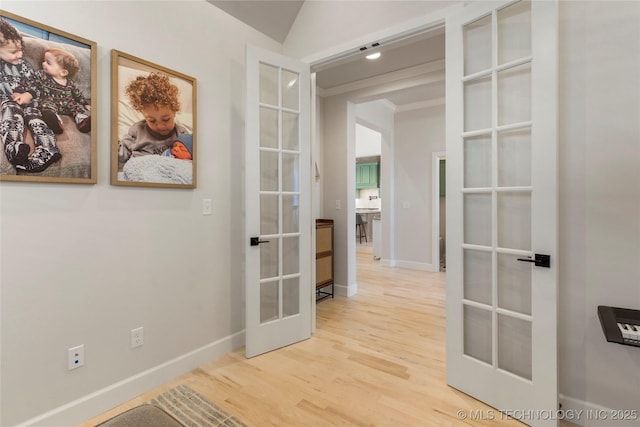 hallway with ornamental molding, french doors, wood finished floors, and baseboards