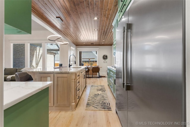 kitchen with wooden ceiling, light wood-style flooring, built in refrigerator, light stone countertops, and a sink