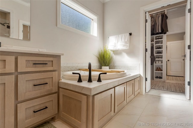 bathroom with a walk in closet, marble finish floor, vanity, and a bath