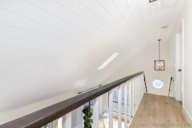 corridor featuring lofted ceiling, an inviting chandelier, wood ceiling, a healthy amount of sunlight, and an upstairs landing