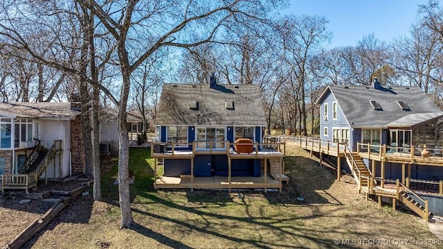 rear view of property featuring stairway, a chimney, and a deck