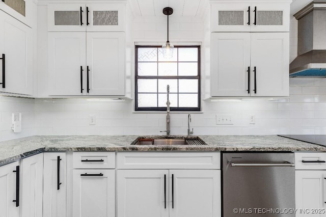 kitchen featuring wall chimney range hood, white cabinetry, backsplash, and a sink