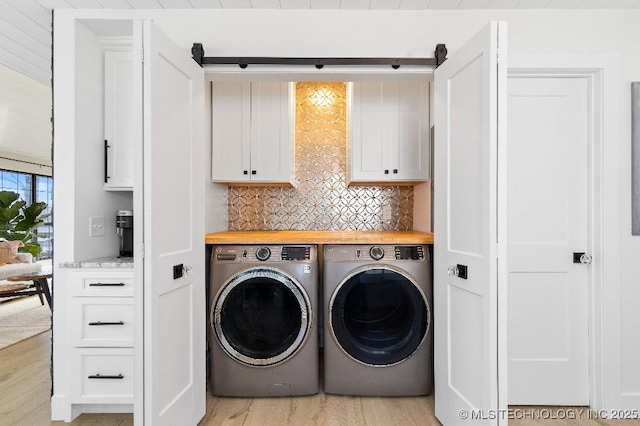 laundry room featuring light wood-type flooring, cabinet space, and separate washer and dryer