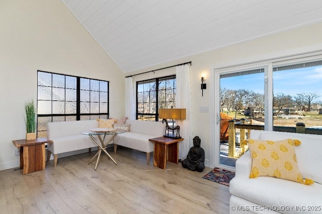 living area featuring lofted ceiling, baseboards, and wood finished floors