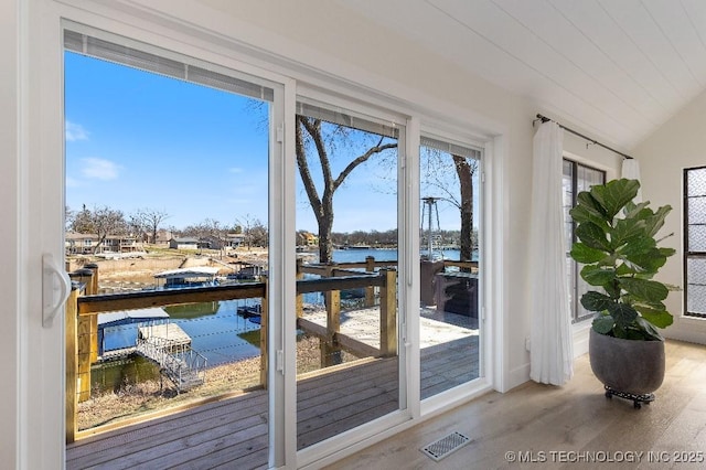 entryway featuring a water view, visible vents, vaulted ceiling, and wood finished floors