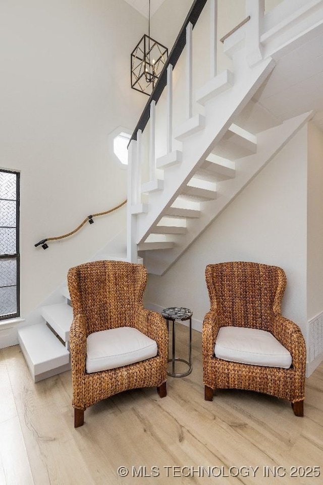 sitting room featuring stairs, wood finished floors, visible vents, and an inviting chandelier