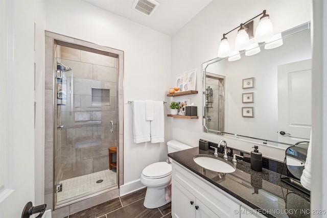 full bath with toilet, vanity, visible vents, baseboards, and a stall shower