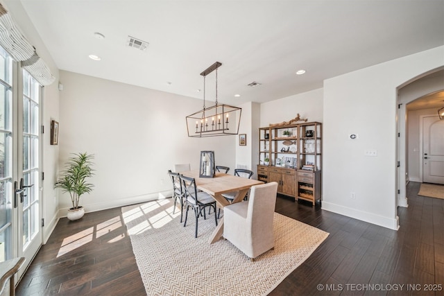 dining space with dark wood-style floors, arched walkways, visible vents, and baseboards