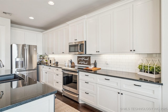 kitchen with appliances with stainless steel finishes, white cabinets, visible vents, and a sink