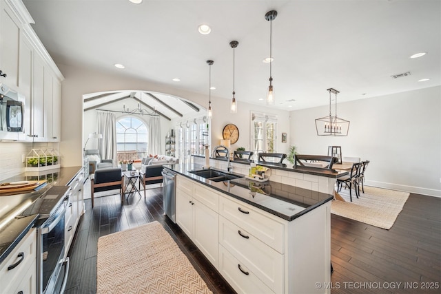 kitchen with appliances with stainless steel finishes, dark countertops, a sink, and visible vents