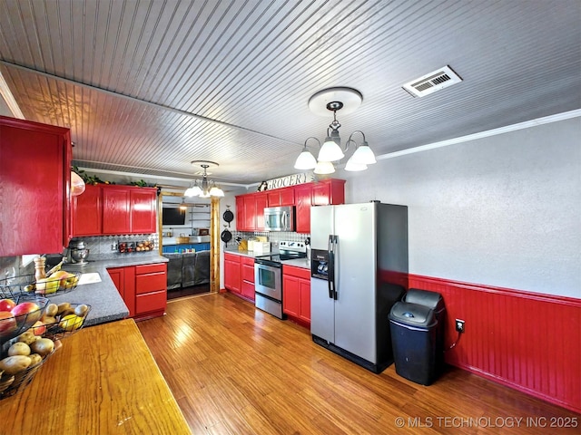 kitchen featuring stainless steel appliances, light wood-style floors, visible vents, and an inviting chandelier