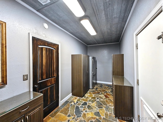 interior space featuring stone tile flooring, ornamental molding, freestanding refrigerator, wooden ceiling, and baseboards