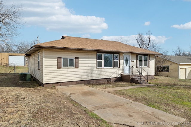 view of front of home with a front yard, cooling unit, and roof with shingles