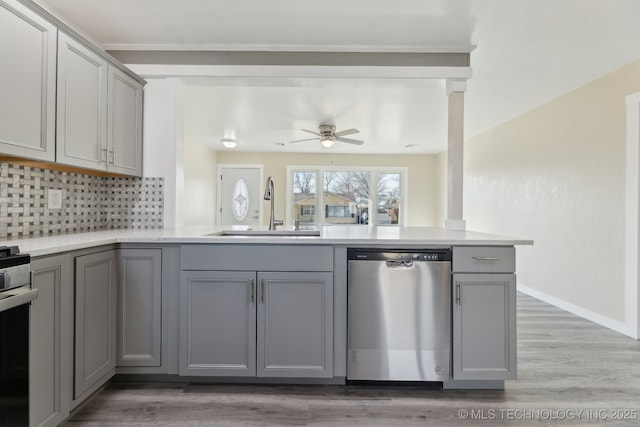 kitchen featuring stainless steel appliances, a sink, light countertops, and gray cabinetry