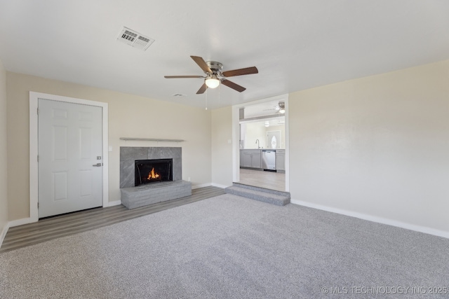 unfurnished living room featuring a fireplace, a sink, carpet flooring, visible vents, and baseboards