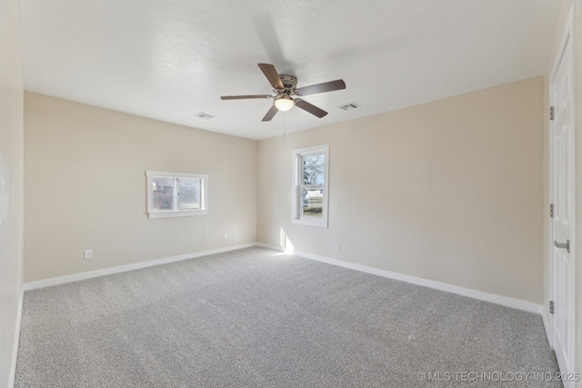 carpeted empty room featuring a ceiling fan, visible vents, and baseboards