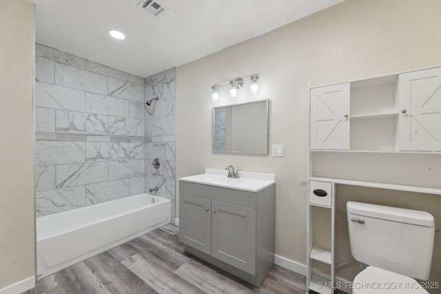 bathroom with toilet, wood finished floors, vanity, visible vents, and tub / shower combination