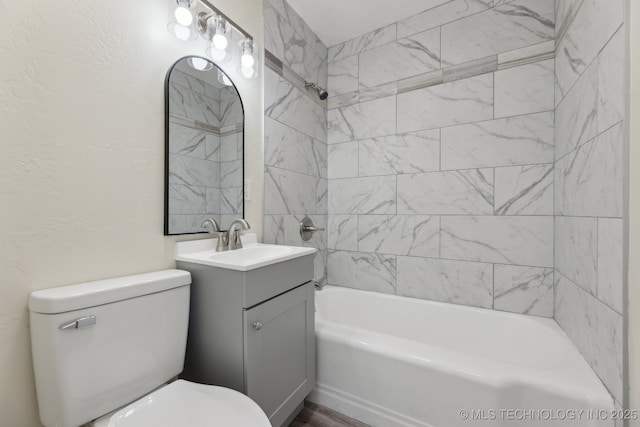 bathroom featuring a textured wall, shower / bathing tub combination, vanity, and toilet