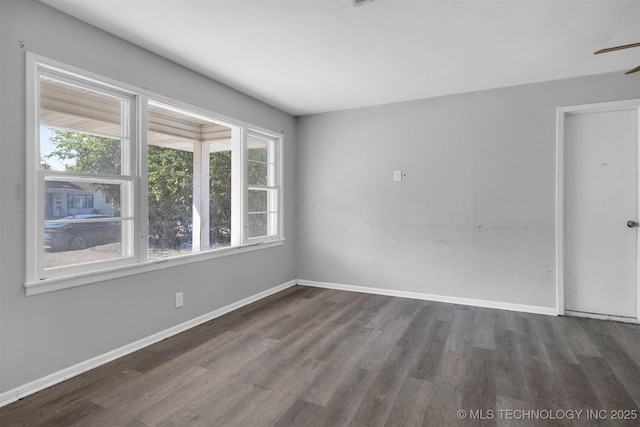 spare room with baseboards and wood finished floors