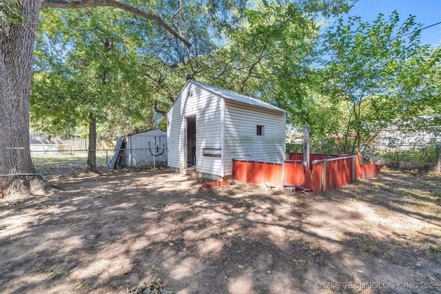 exterior space featuring a storage shed, metal roof, an outbuilding, and fence