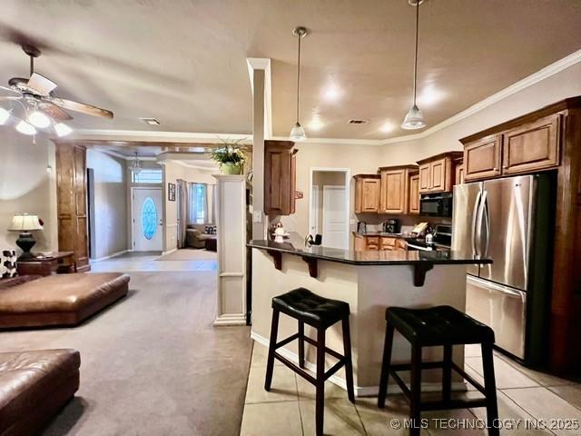 kitchen with black microwave, a breakfast bar, range with electric cooktop, freestanding refrigerator, and dark countertops