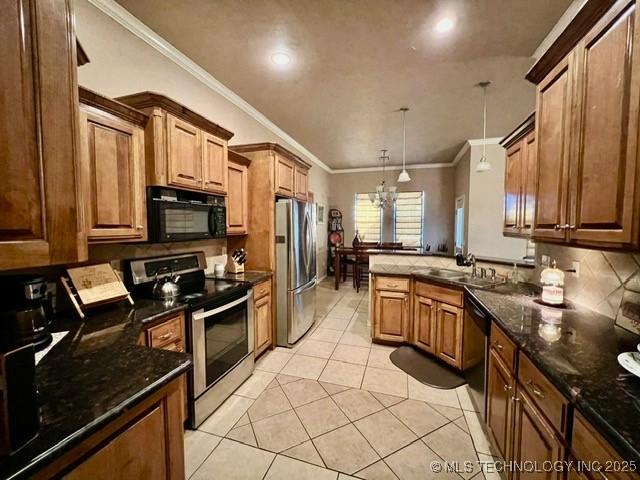 kitchen with light tile patterned floors, stainless steel appliances, ornamental molding, a sink, and a peninsula