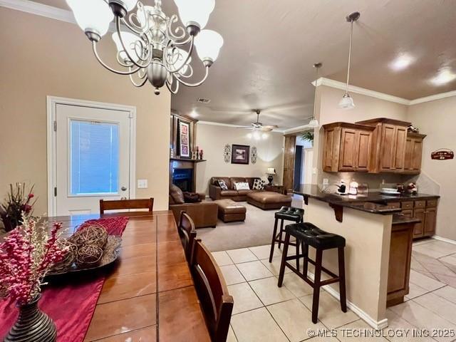 kitchen with ornamental molding, brown cabinetry, dark countertops, and a kitchen breakfast bar