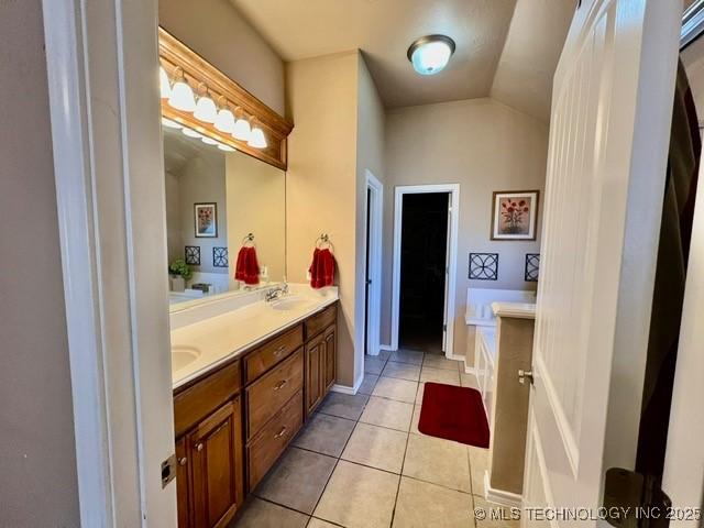 full bathroom featuring double vanity, vaulted ceiling, a sink, and tile patterned floors