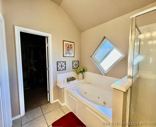 full bath featuring vaulted ceiling, a tub with jets, tile patterned flooring, and a shower stall