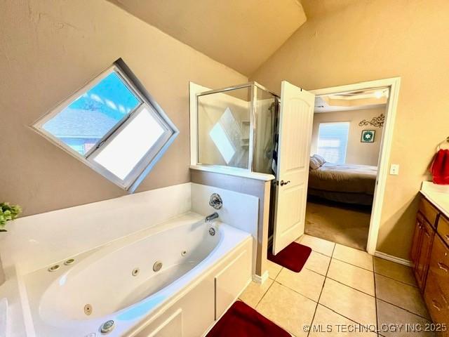 full bathroom featuring a stall shower, connected bathroom, lofted ceiling, a tub with jets, and tile patterned flooring