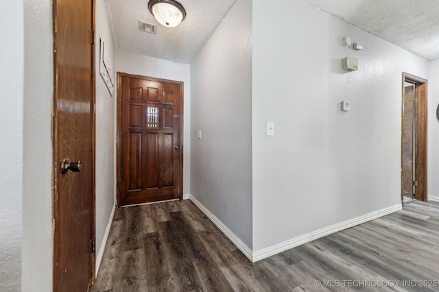 doorway with visible vents, dark wood finished floors, a textured ceiling, and baseboards