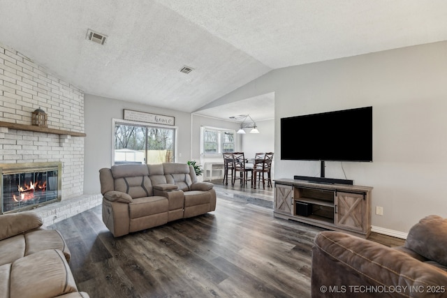 living room featuring a textured ceiling, a fireplace, visible vents, vaulted ceiling, and dark wood-style floors