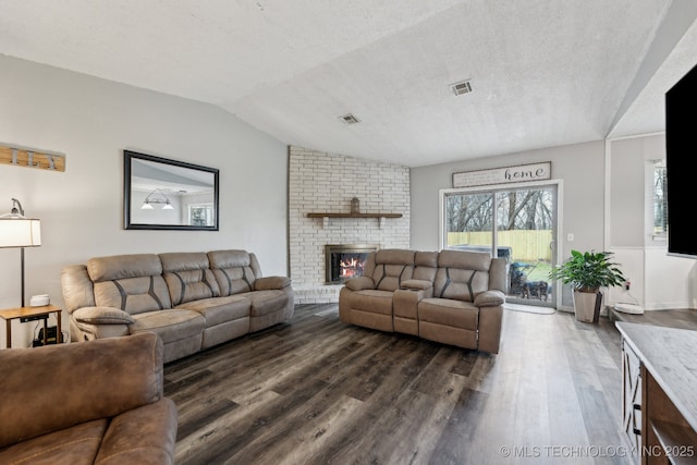 living area featuring dark wood-style floors, lofted ceiling, visible vents, and a fireplace