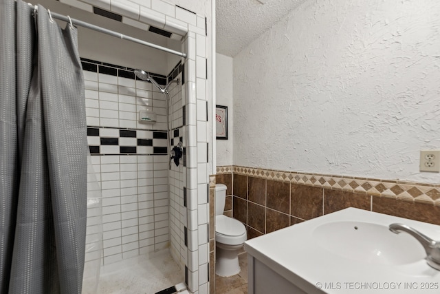 bathroom featuring a textured wall, toilet, a textured ceiling, a shower stall, and tile walls