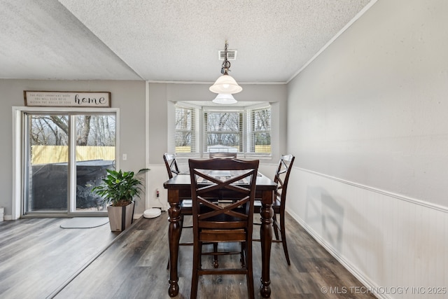 dining area with visible vents, a wainscoted wall, ornamental molding, wood finished floors, and a textured ceiling