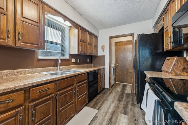 kitchen with dark wood-style floors, light countertops, a sink, a textured ceiling, and black appliances