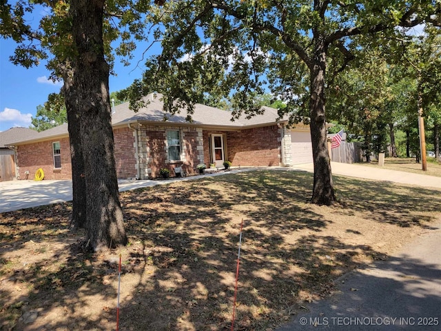 ranch-style house featuring a garage, driveway, brick siding, and fence