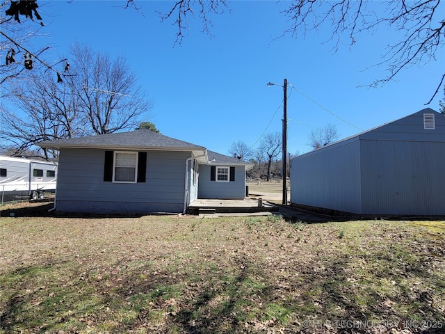 rear view of property featuring a lawn and an outbuilding