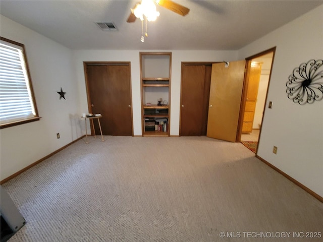 unfurnished bedroom with light colored carpet, a ceiling fan, baseboards, multiple closets, and visible vents