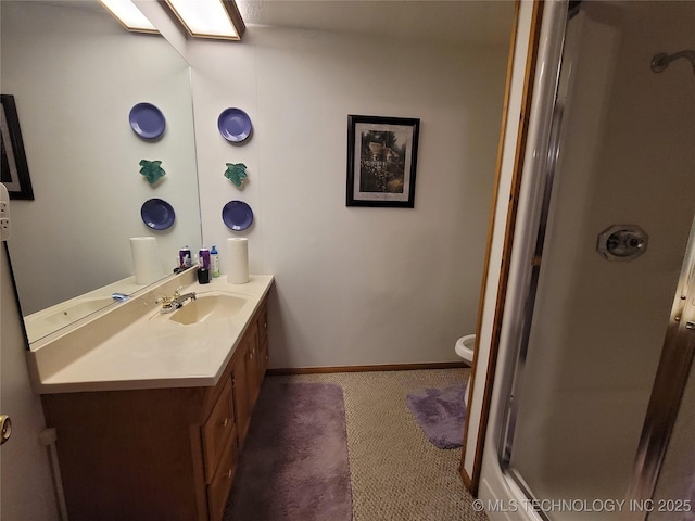 bathroom featuring a skylight, a shower with door, toilet, vanity, and baseboards