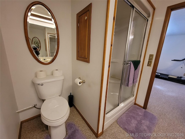 bathroom featuring a stall shower, toilet, and baseboards