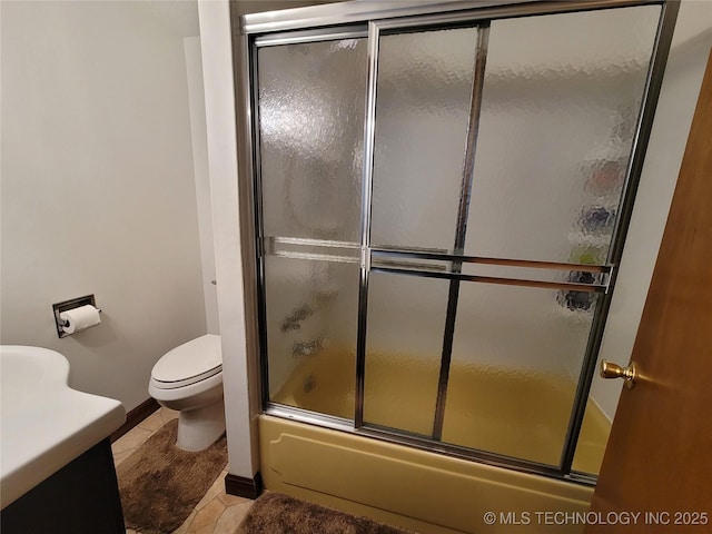 bathroom featuring baseboards, toilet, tile patterned flooring, combined bath / shower with glass door, and vanity