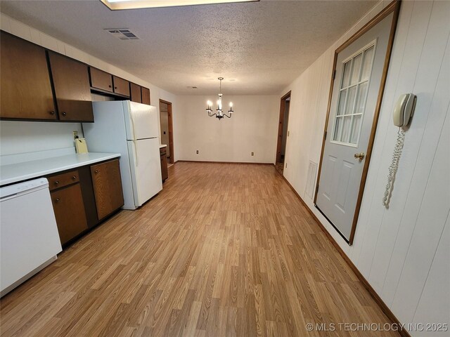 kitchen with a notable chandelier, white appliances, visible vents, light countertops, and light wood finished floors