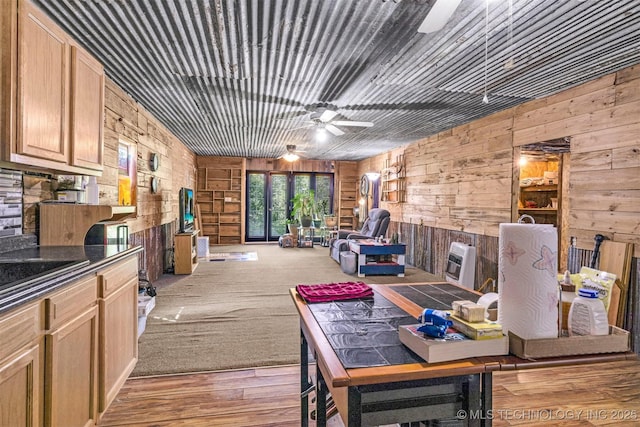 interior space featuring ceiling fan, open floor plan, dark countertops, and wooden walls