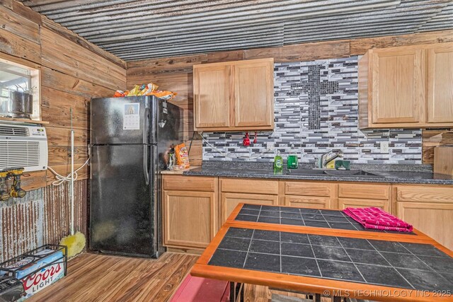 kitchen featuring dark countertops, light brown cabinetry, a sink, and freestanding refrigerator