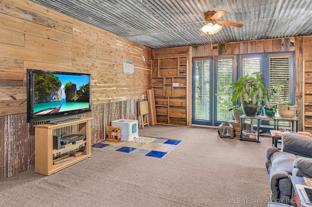 living area with a ceiling fan, carpet flooring, and wooden walls