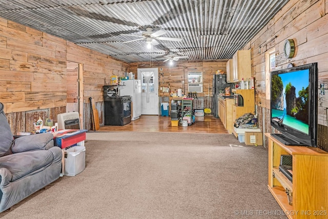 carpeted living area featuring a ceiling fan and wood walls