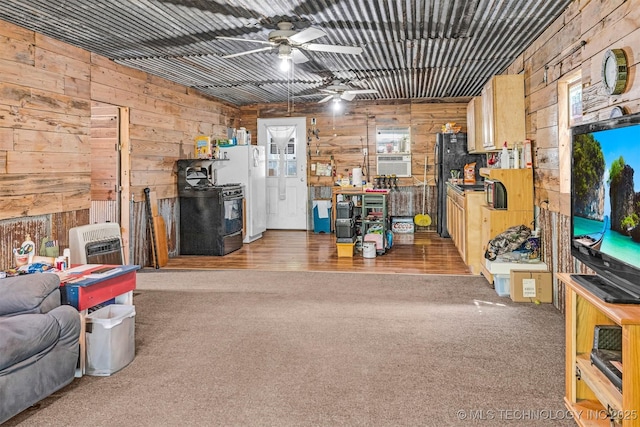 interior space with a ceiling fan, carpet, and wooden walls