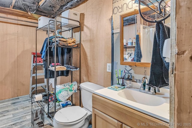 half bath featuring vanity, toilet, and wood finished floors